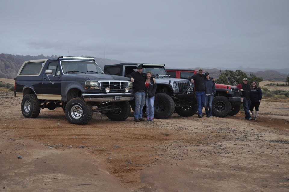 Dark blue 1991 Ford Bronco with lifted suspension and light bar parked with other off-road vehicles