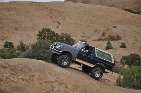 1991 Ford Bronco - This 1991 Ford Bronco is navigating a challenging off-road trail in a desert environment.