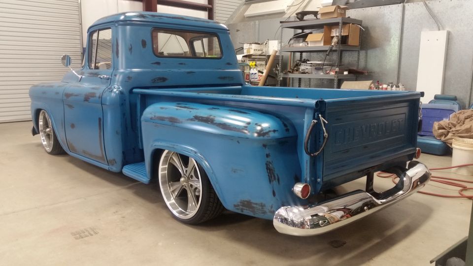 Blue pickup truck with worn paint and custom wheels, viewed from a 3/4 front angle