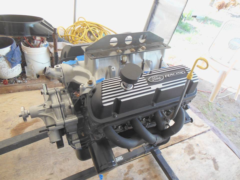 Ford Racing valve covers on an engine assembly mounted on a stand. Oil dipstick is visible