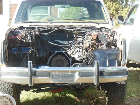 1984 Ford Bronco - Front view of a white Ford Bronco with its engine compartment exposed, revealing the transmission and extensive wiring.