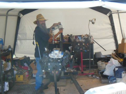 1984 Ford Bronco - A man is working on an engine in a garage, with another engine visible in the background.