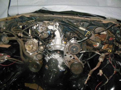 1984 Ford Bronco - The engine bay of a vehicle is shown with many parts and wiring exposed, suggesting maintenance or repair work.