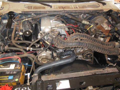 1984 Ford Bronco - Engine bay view showing V8 engine components, battery, and radiator.