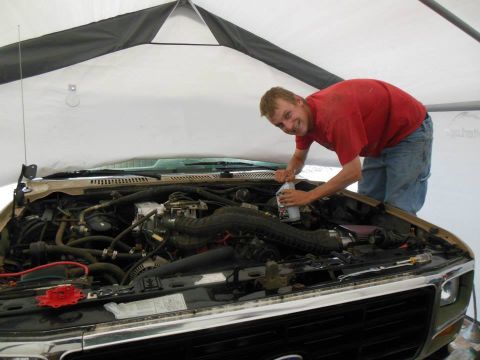 1984 Ford Bronco - A person is tending to the engine of a vehicle, likely performing maintenance.