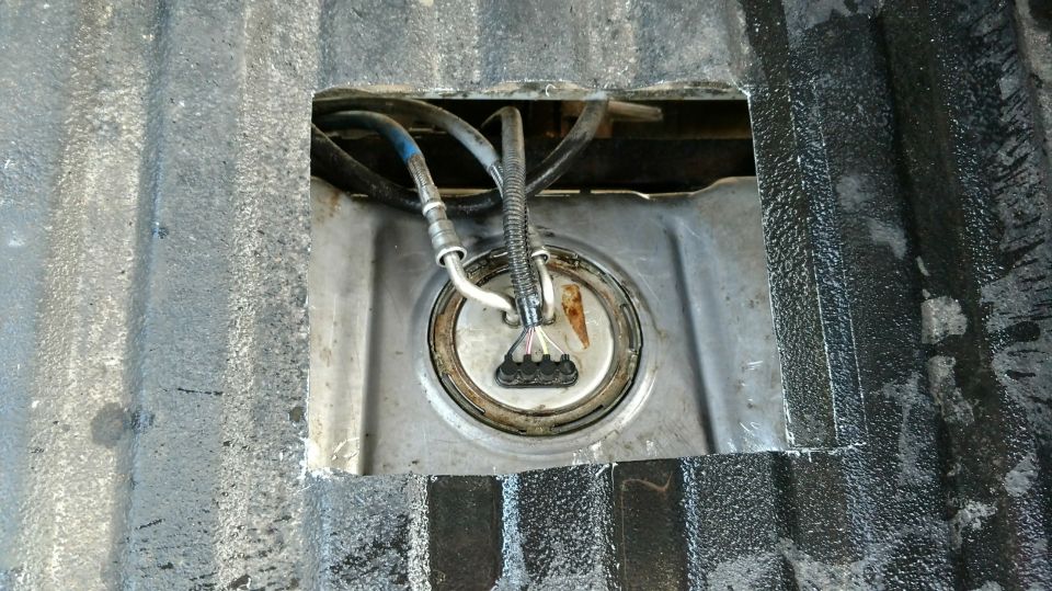 Fuel pump assembly accessed through a cut-out in a textured metal surface
