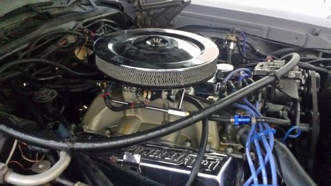 1976 Ford Ranchero - Close-up view of an engine's intake system, a chrome air cleaner and prominent blue spark plug wires.