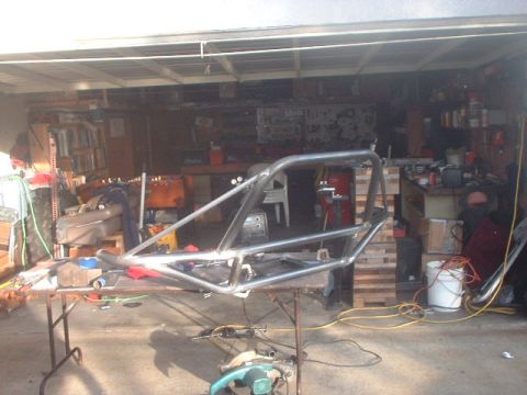 1996 Ford Bronco - A custom roll cage frame is shown on a workbench in a cluttered garage setting.
