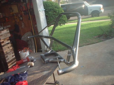 1996 Ford Bronco - A custom roll cage is on a workbench, with a white Ford truck visible in the background.