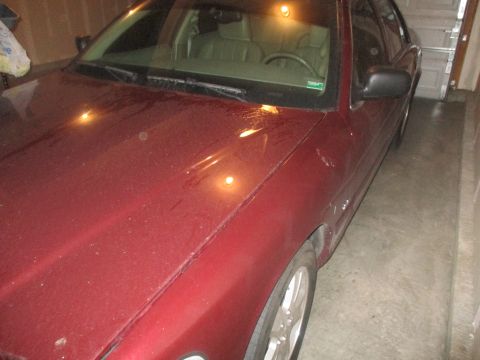 2004 Ford Crown Victoria - A red sedan is parked inside a garage, with its interior visible through the windshield.