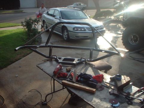 1996 Ford Bronco - Custom roll cage fabrication in progress, with a silver sedan and part of an off-road vehicle visible.