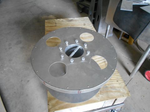 1992 Ford Bronco - A metal component with multiple holes and bolted connections is shown, resting on a wooden surface.