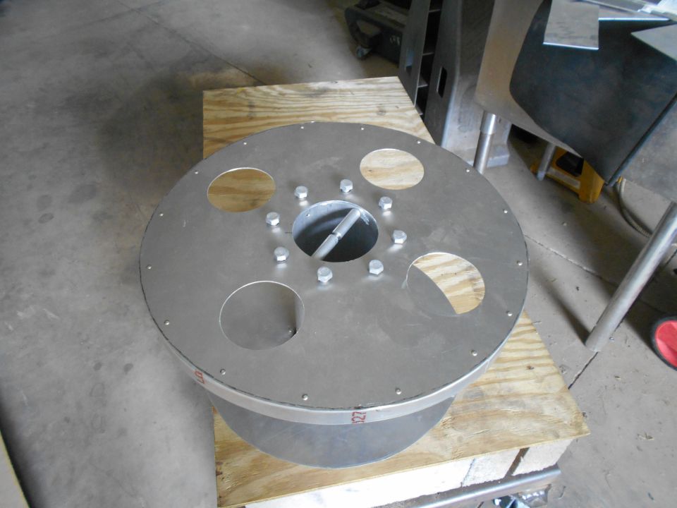 Metal part with circular cutouts and bolts, resting on wood