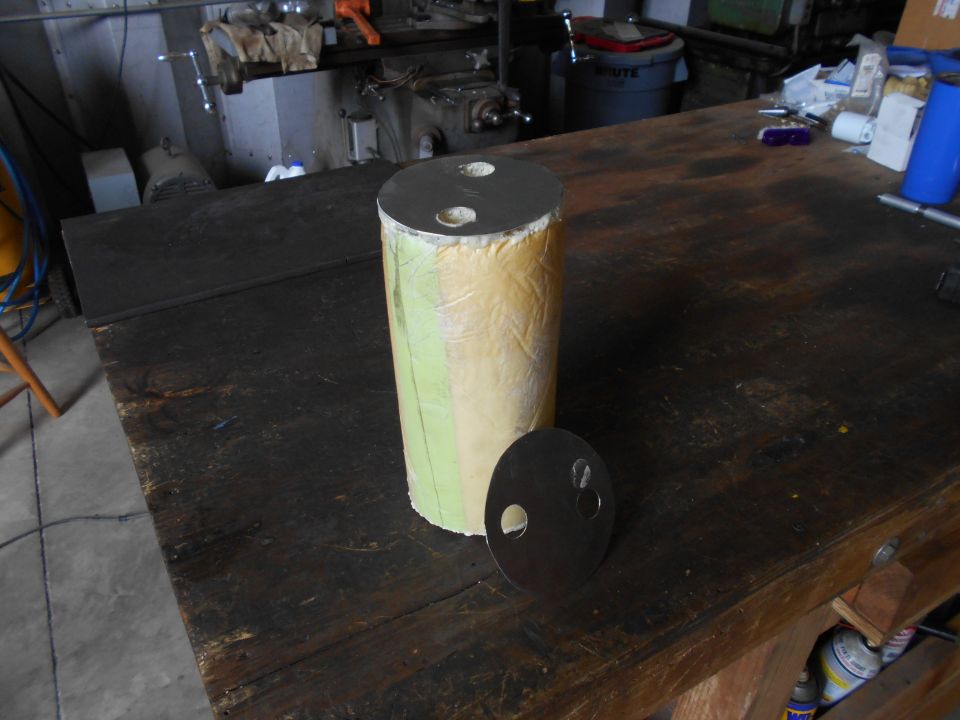 cylindrical part with two metal caps, one on top and one beside it, on a workbench
