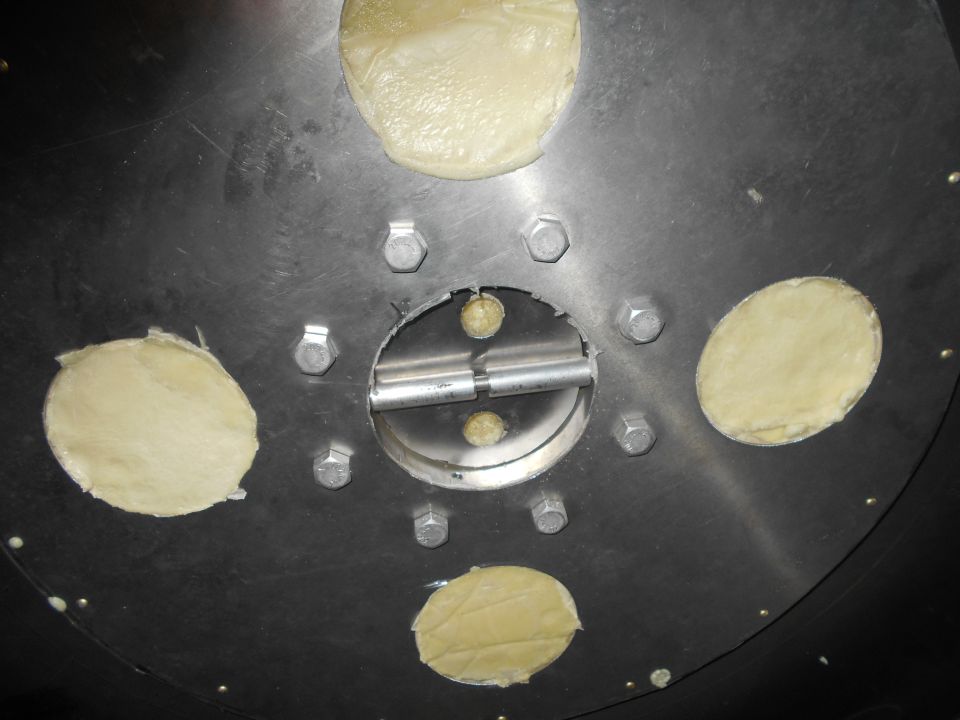 Metal plate with six bolts, a central circular opening with metal shafts, and four circular cutouts covered with yellow material