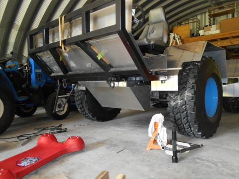 1992 Ford Bronco - A custom-built vehicle with large tires and a cargo bed is shown, with a blue tractor visible in the background.