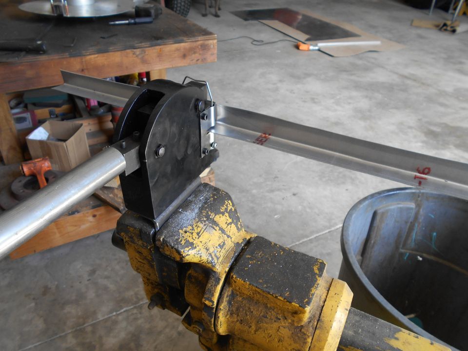 metal stock being bent in a yellow vise with a black tool
