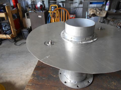 1992 Ford Bronco - A metal disc with a central pipe assembly sits on a wooden surface in a workshop environment.