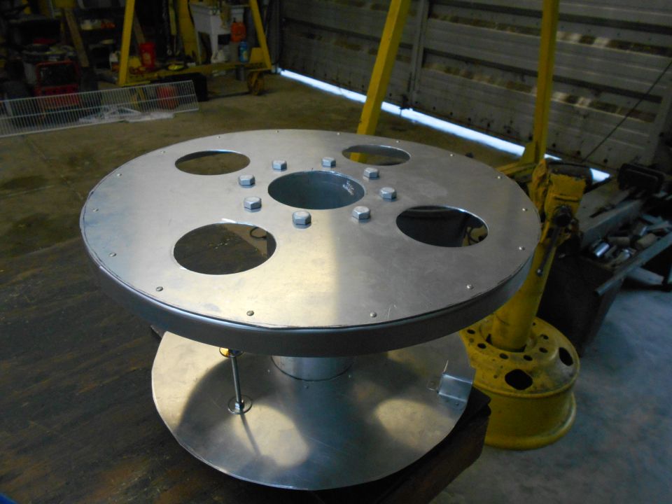 Metal spool with large holes and bolts, on a stand