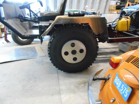 1992 Ford Bronco - A custom-built vehicle with oversized tires is parked next to a vintage orange Volkswagen Beetle.