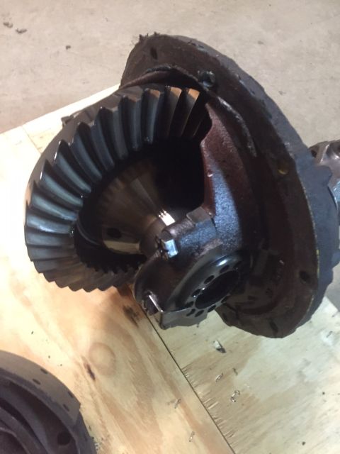 1982 Ford Bronco - A close-up view of a differential housing with a large ring gear attached. The metal housing appears to be dark and greasy, with some wear…