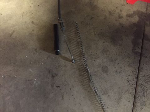 1982 Ford Bronco - A black cylindrical part and a long, thin, coiled spring lie on a concrete floor.