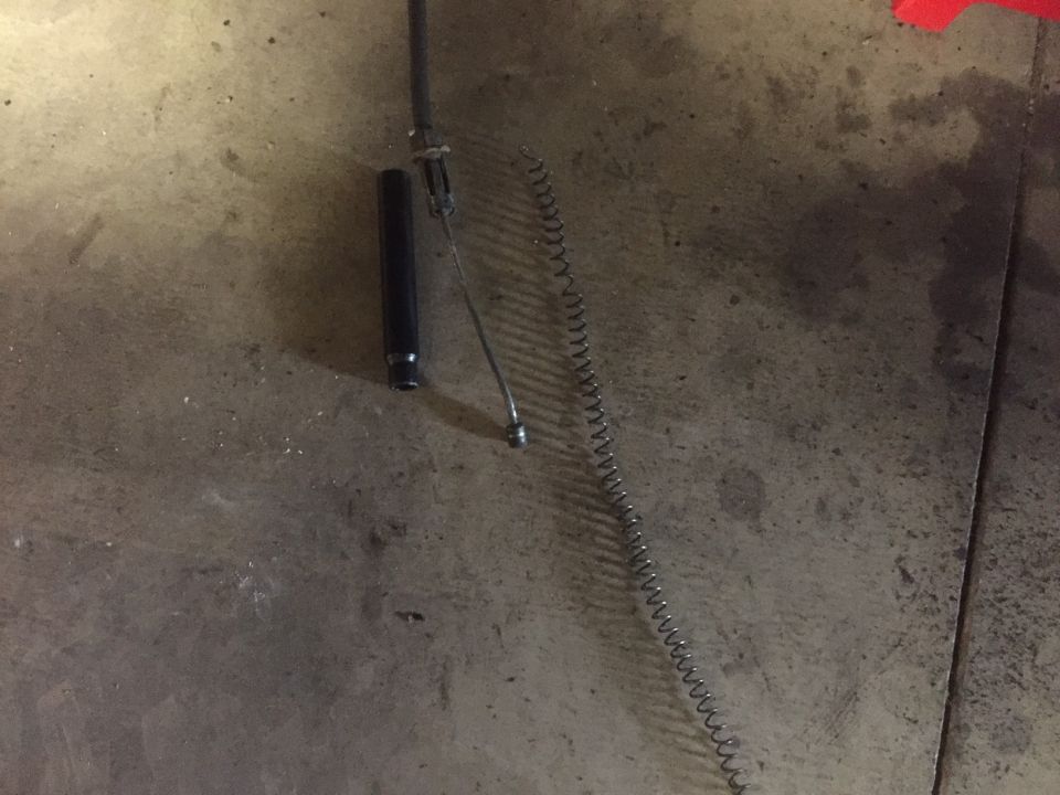 Black cylinder and coiled spring on concrete floor