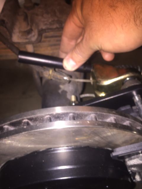 1982 Ford Bronco - A hand is shown adjusting a black component that appears to be part of a brake system, near a brake rotor and caliper. The context suggests…