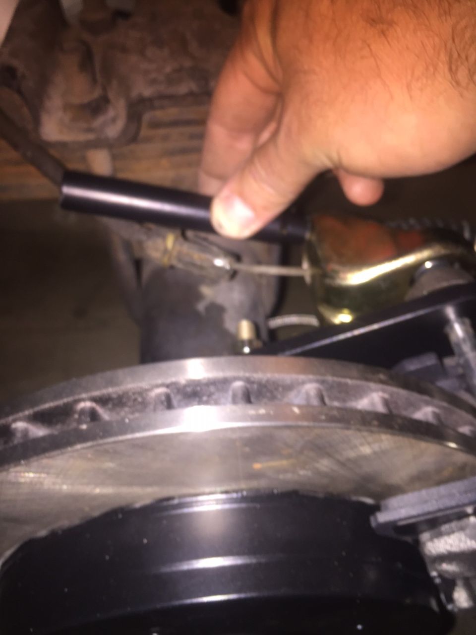 Hand adjusting brake component near rotor and caliper on a 1982 Ford Bronco.