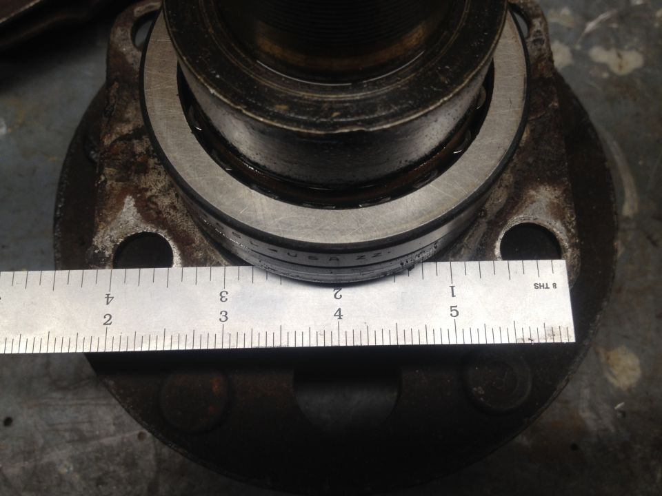 Close-up of a metal ruler measuring a vehicle part, likely a wheel hub.