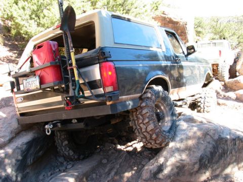 1996 Ford Bronco - This 1996 Ford Bronco is equipped for off-roading with a rear-mounted gas can and shovel, navigating rocky terrain.