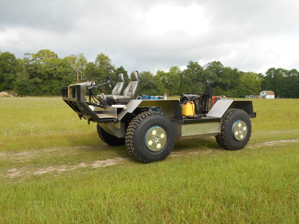 Custom four-wheel drive vehicle with large tires and two seats in a grassy field.