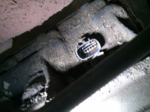 1996 Ford Bronco - A close-up view shows a dirty electrical connector with visible pins and some yellowish fluid inside. The connector is mounted on a dark, g…