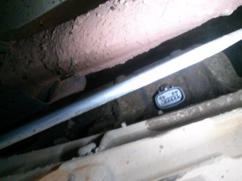 1996 Ford Bronco - A gray electrical connector with six pins is visible under the chassis of a vehicle, possibly a 1996 Ford Bronco, near a metal pipe.