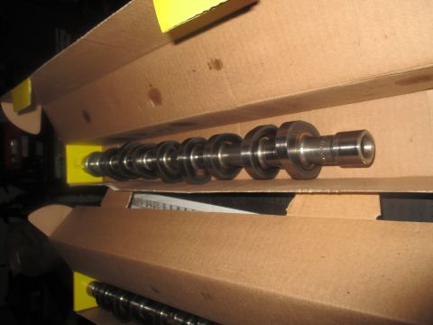 2004 Ford Crown Victoria - Two camshafts are shown inside cardboard boxes. The top camshaft has multiple lobes and is resting on yellow supports within the box.