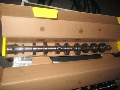 2004 Ford Crown Victoria - A camshaft is shown inside a cardboard box with yellow trim. The camshaft is a long metal rod with several lobes and appears to be new.