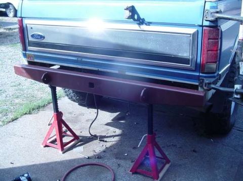1996 Ford Bronco - Rear view of a blue Ford Bronco with its bumper removed and supported by jack stands.