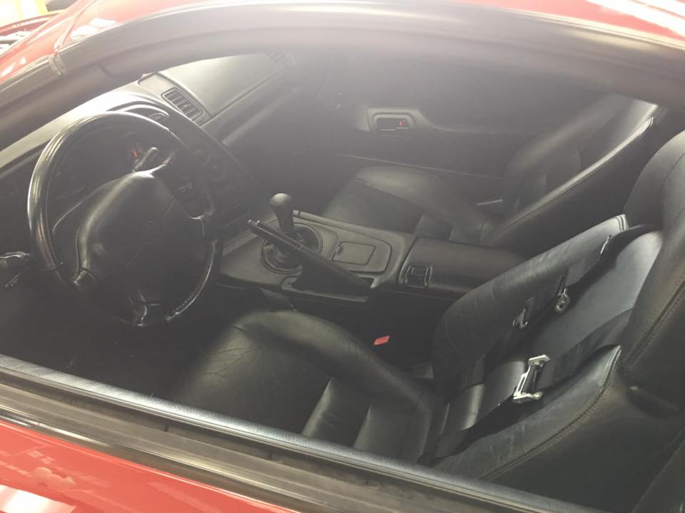 Interior of a red 1994 Toyota Supra with black leather seats and steering wheel.