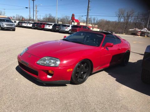 1994 Toyota Supra - This red sports car has a distinctive body style and black aftermarket wheels.
