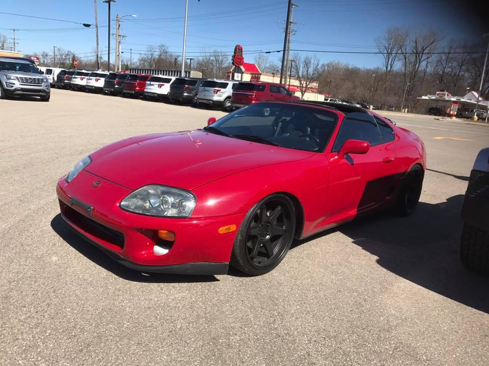 Red sports car with black wheels parked in a lot