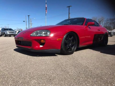 1994 Toyota Supra - A red 1994 Toyota Supra is shown from the front quarter angle, parked outdoors on a sunny day.