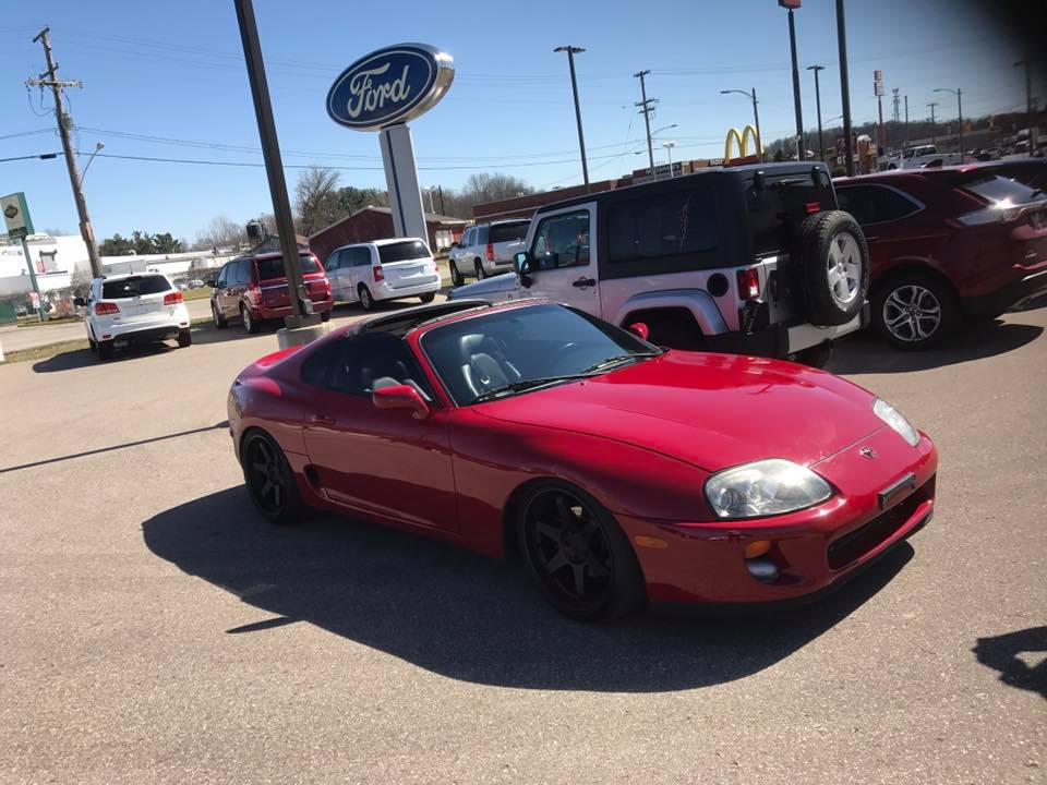 Red 1994 Toyota Supra parked in lot with other vehicles and a Ford sign