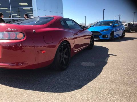1994 Toyota Supra - A red 1994 Toyota Supra is parked next to a blue Ford Focus on a sunny day.