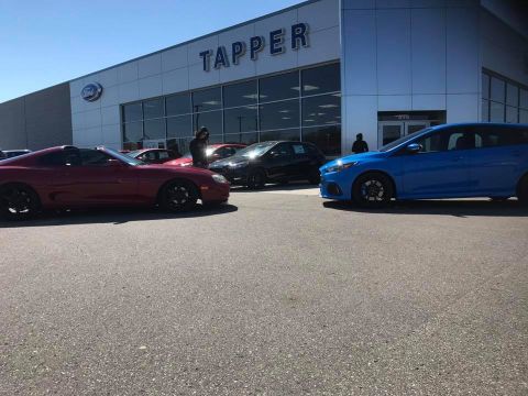 1994 Toyota Supra - A red 1994 Toyota Supra is parked in front of a dealership, with other vehicles visible.
