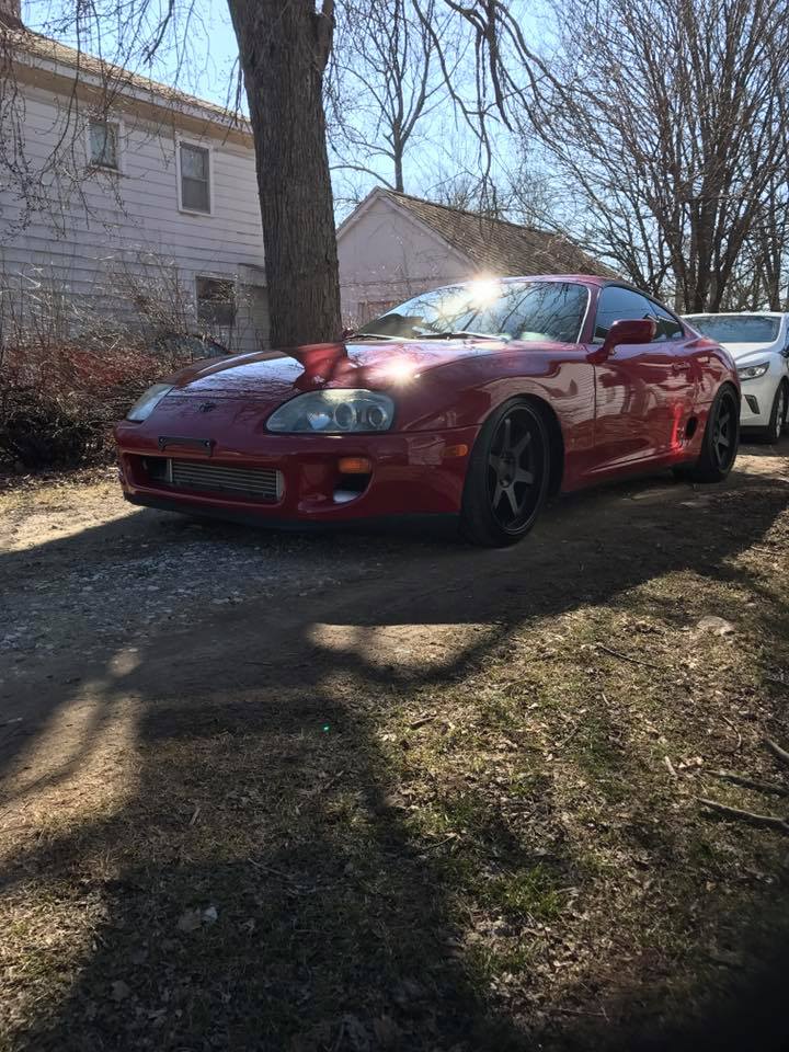 Red Toyota Supra with aftermarket wheels and intercooler visible