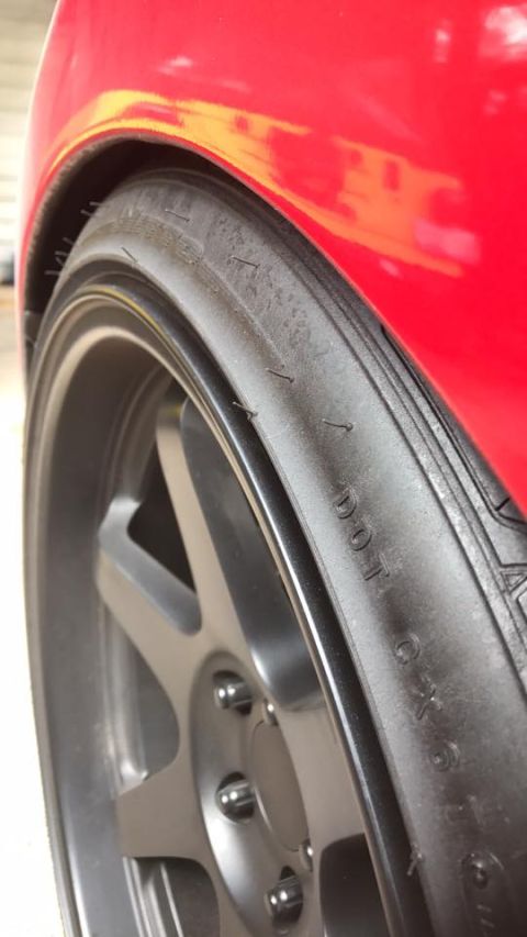 1994 Toyota Supra - Close-up of a red car's fender and wheel assembly, showing a custom gray wheel.
