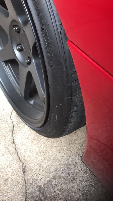 1994 Toyota Supra - Aftermarket wheel and tire fitted to a red vehicle, detail shot of the fender and tire.