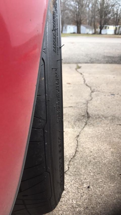 1994 Toyota Supra - A close-up view of a vehicle's tire and part of its red bodywork is shown against a cracked concrete surface.