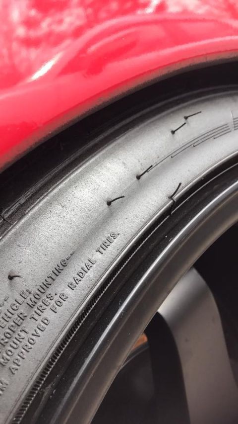 1994 Toyota Supra - Close-up of a red car's fender and tire, with visible text indicating 'FOR RADIAL TIRES.'