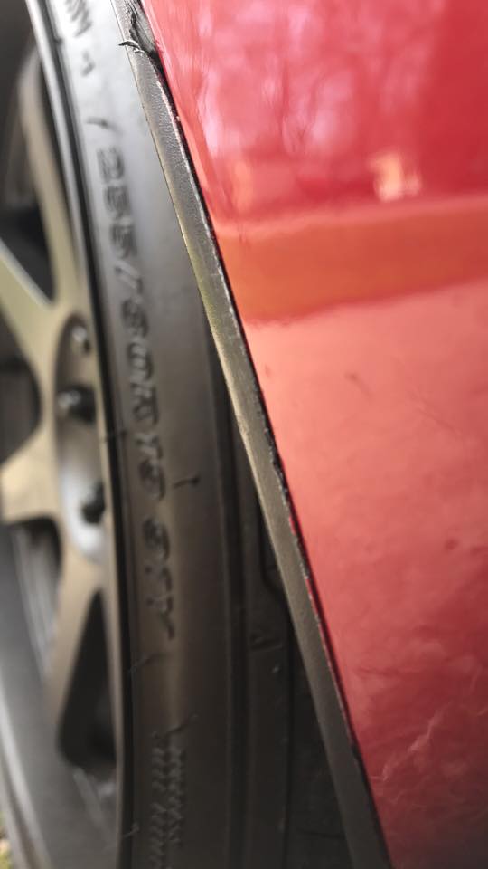 Red car wheel well with tire and rim visible